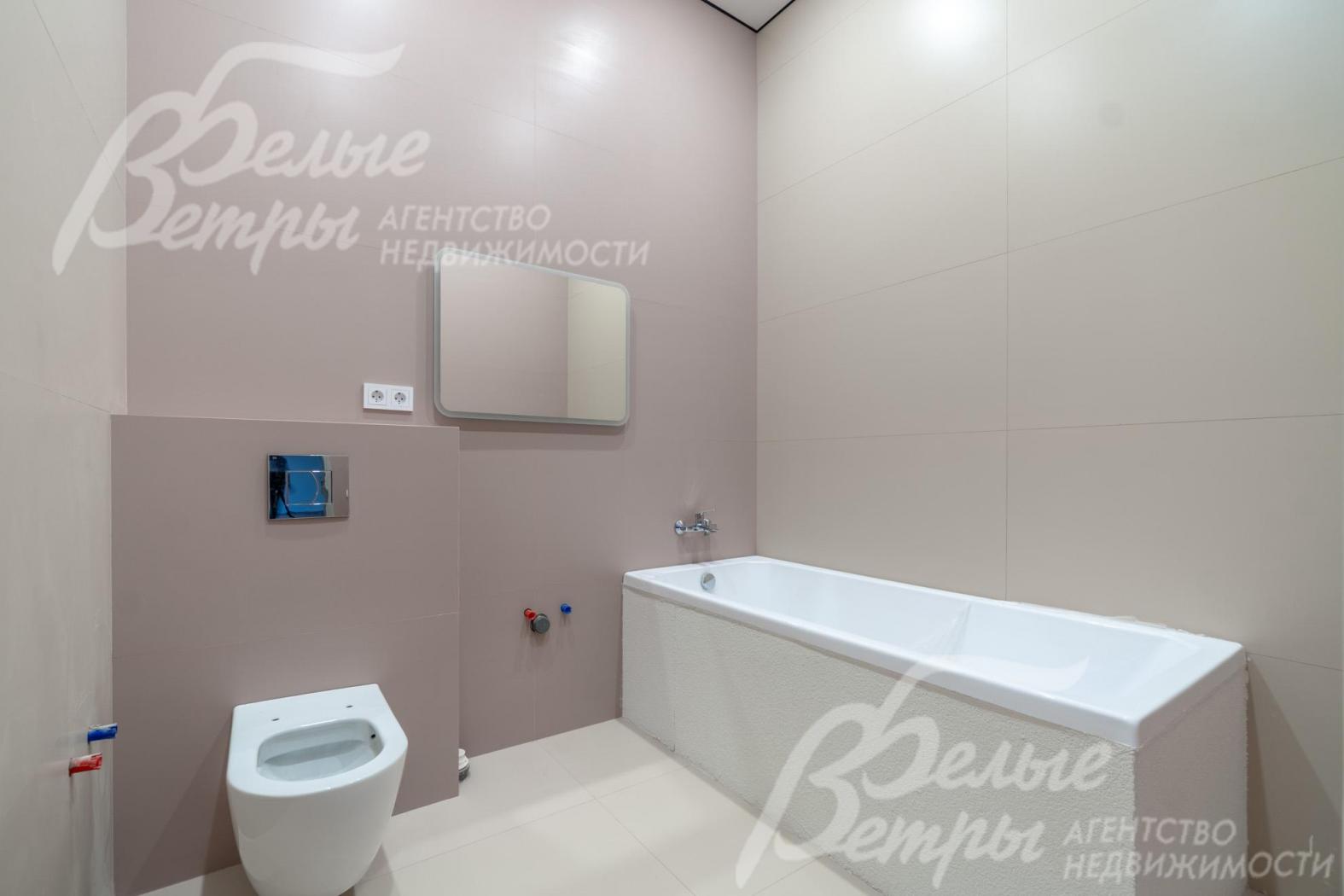 Один из санузлов на втором этаже с плиткой в светло-серых оттенках и с ванной