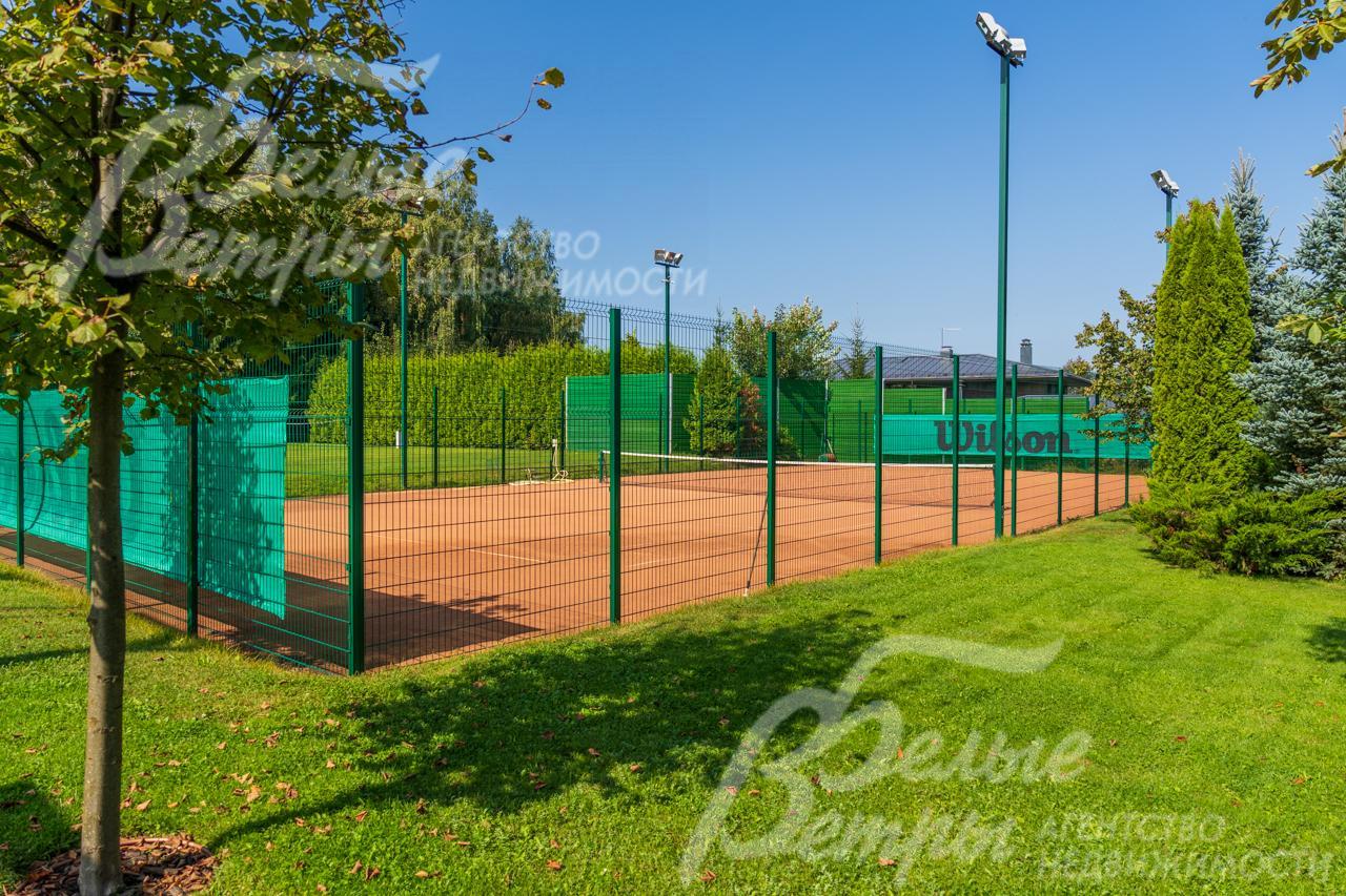 Теннисный корт с профессиональным покрытием и вечерним освещением.