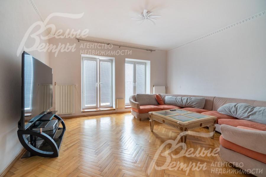 Жилая комната на третьем этаже с большими окнами, диванной группой и широкоформатным телевизором