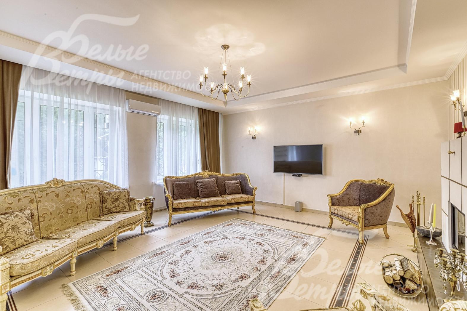 В гостиной - большие окна с видом на участок, установлен телевизор