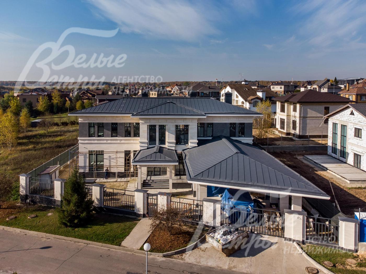 Выразительный натуральный камень и гранит на фасаде дома, стильные тёмно-серые витражи, гармонирующие с большими свесами крыши такого же цвета