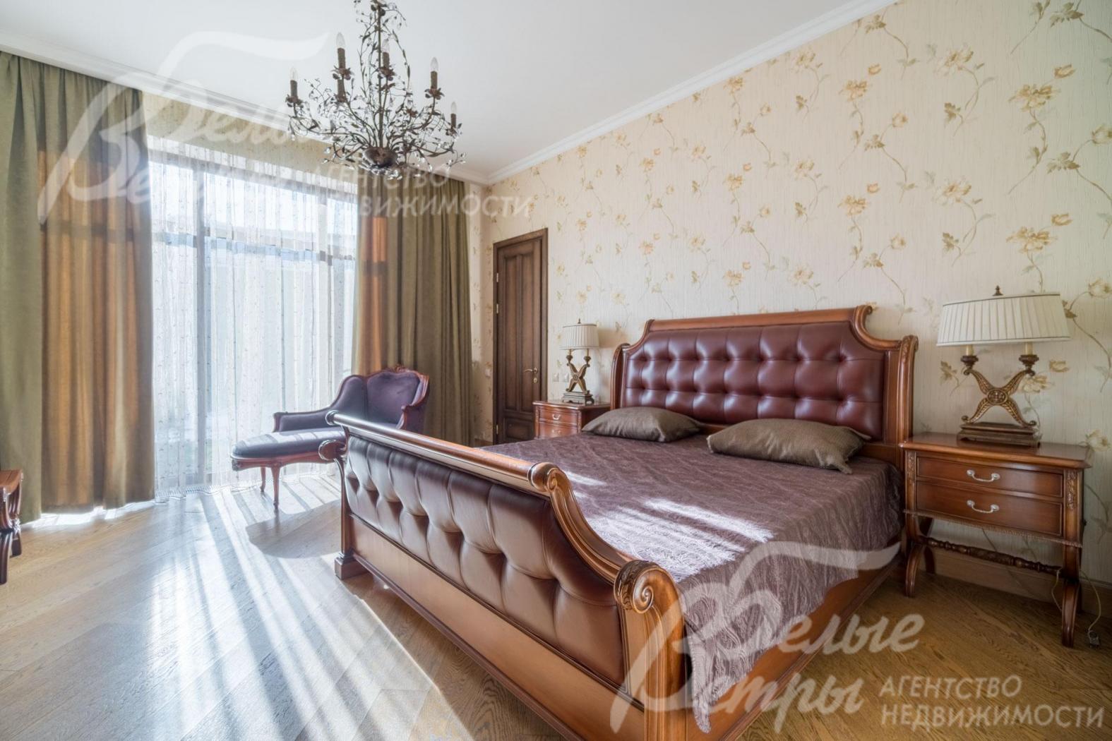 Спальная на первом этаже с большим окном в пол. В спальне - дубовый паркет, роскошная люстра, дорогостоящая мебель, зонирование обоями