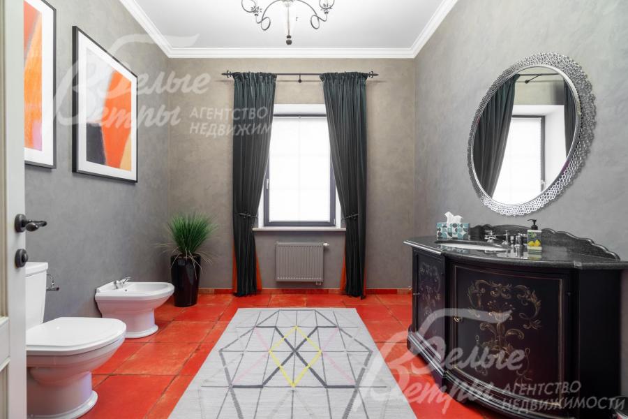 Санузел на первом этаже с насыщенным акцентным терракотово-красным полом, тумбой под раковину с изысканным орнаментом и картинами