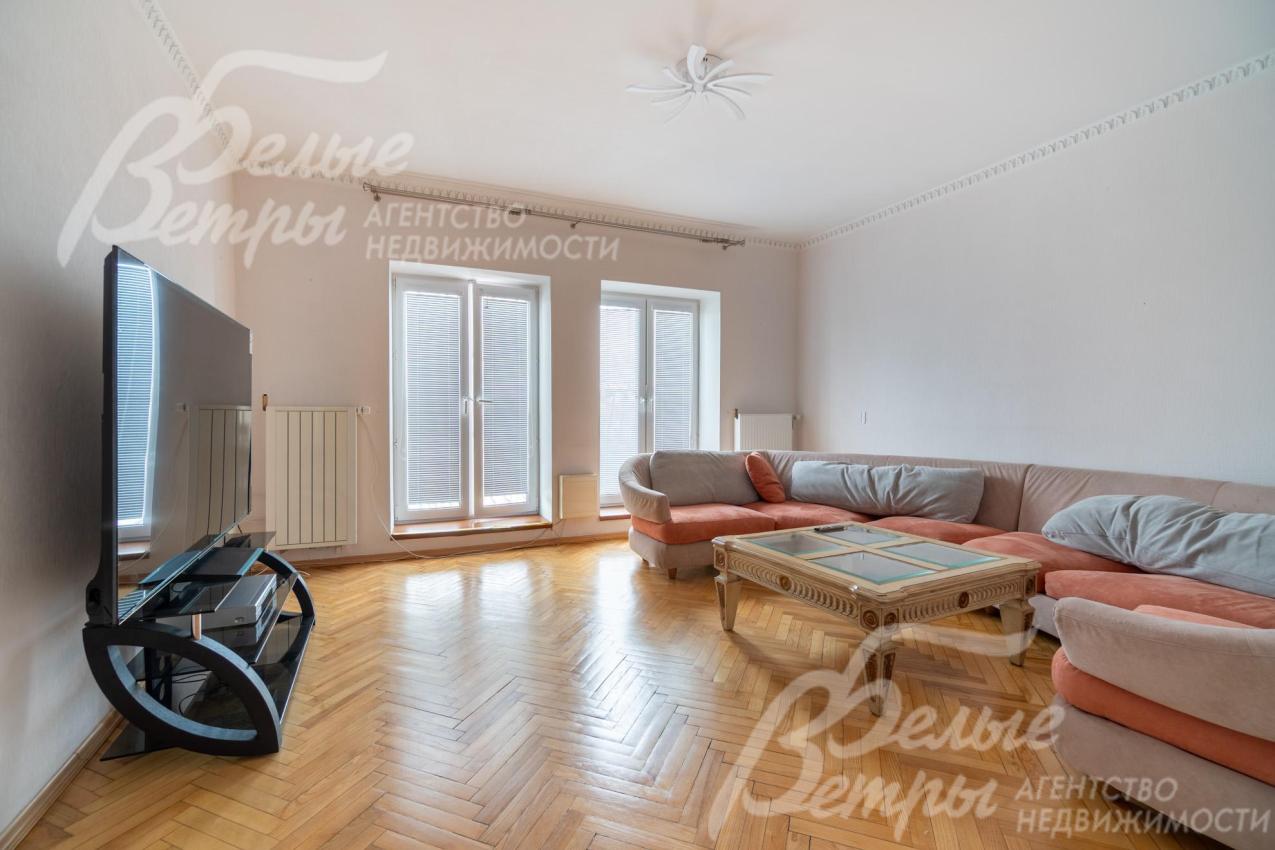 Жилая комната на третьем этаже с большими окнами, диванной группой и широкоформатным телевизором