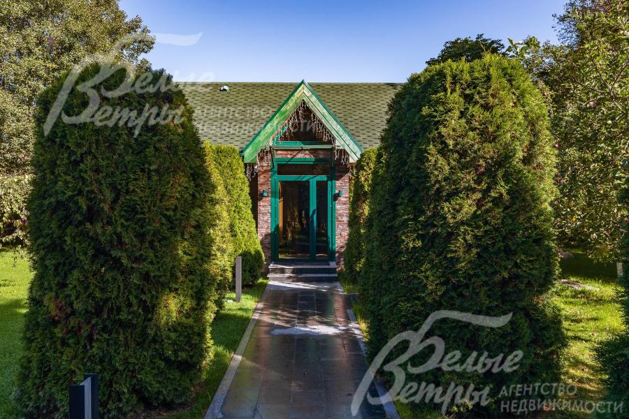 К гостевому дому ведёт вымощенная дорожка, обрамлённая живой изгородью из туй