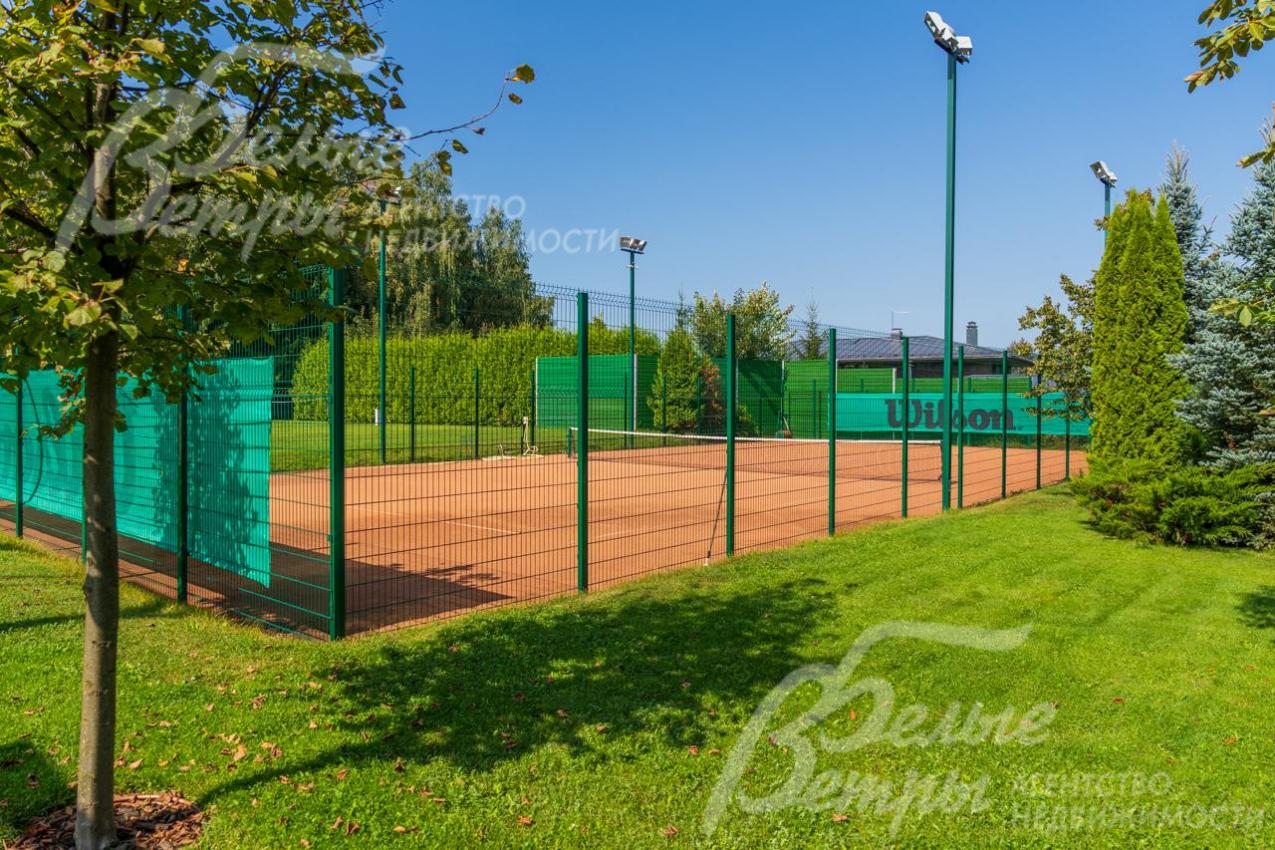 Теннисный корт с профессиональным покрытием и вечерним освещением.