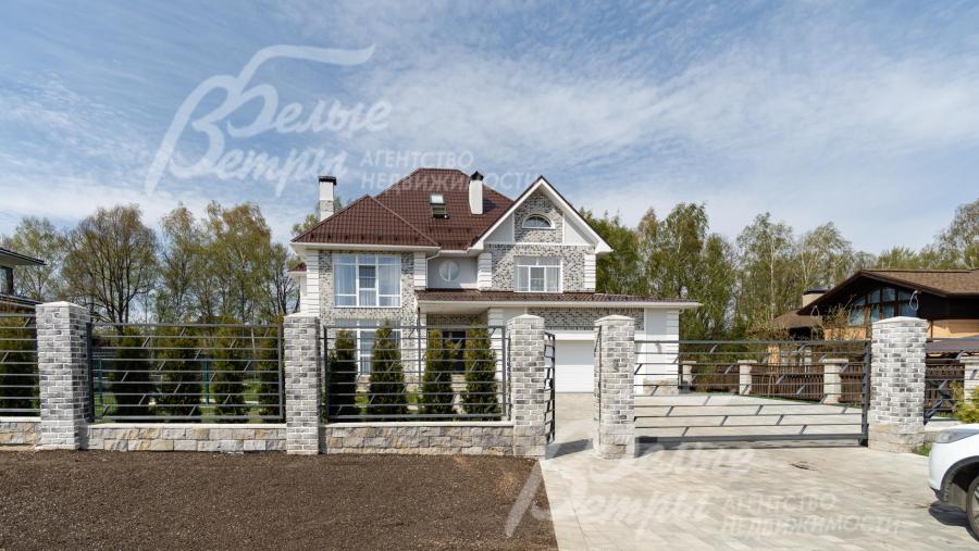 Спереди металлический прозрачный забор на каменных столбах с бетонным цоколем