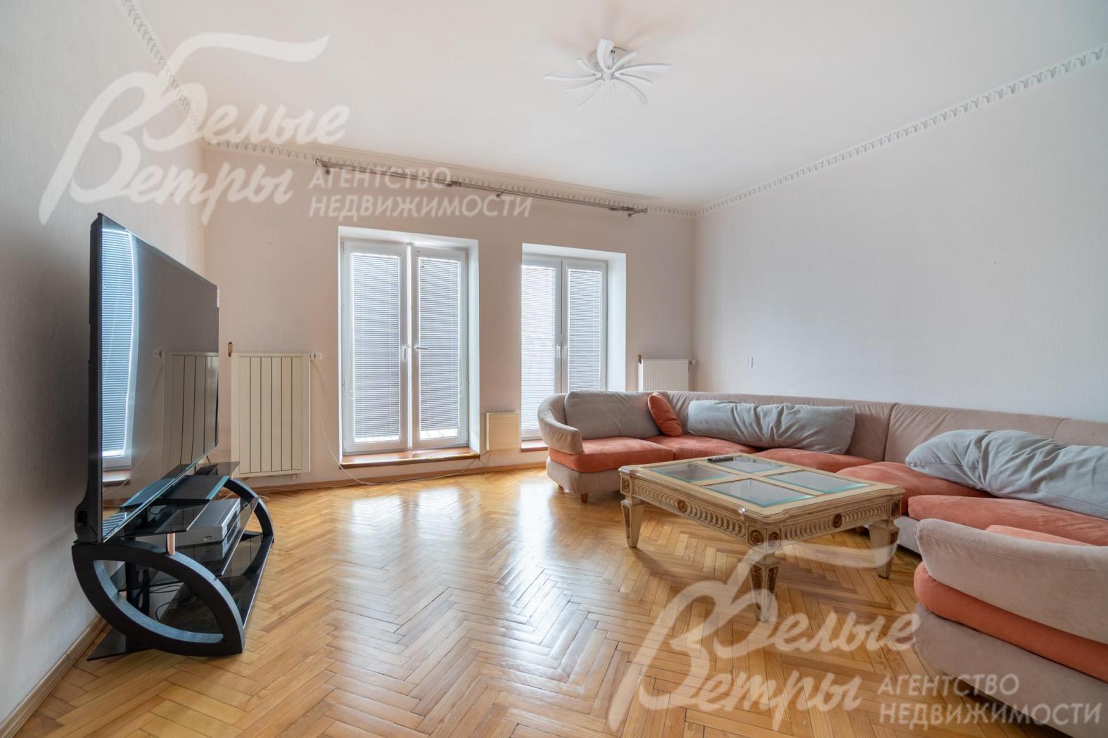 Жилая комната на третьем этаже с большими окнами, диванной группой и широкоформатным телевизором