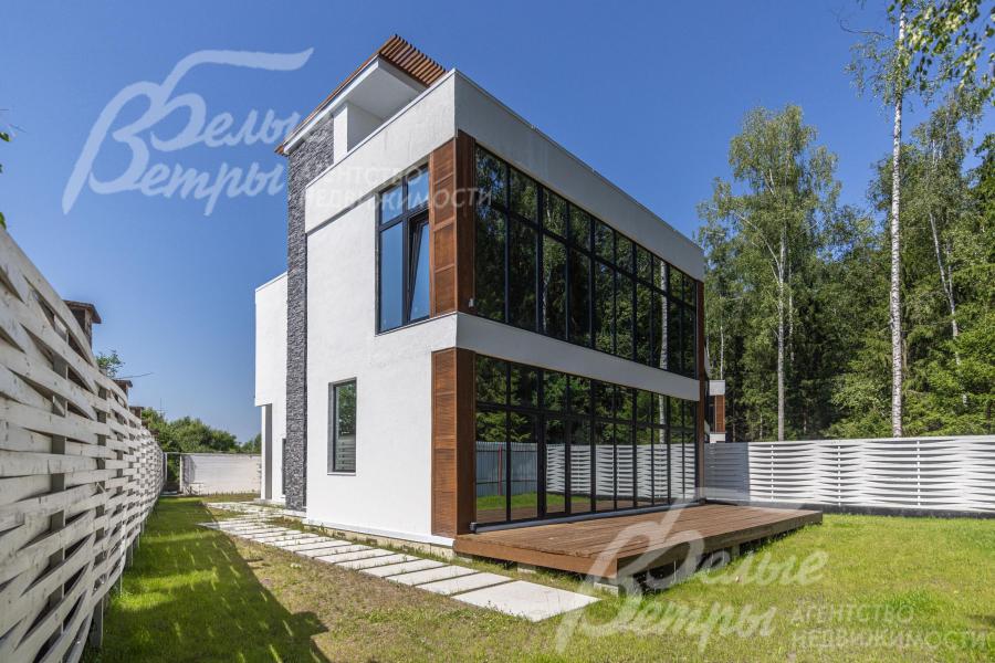 Тыльный фасад дома со стеклянной стеной и террасой