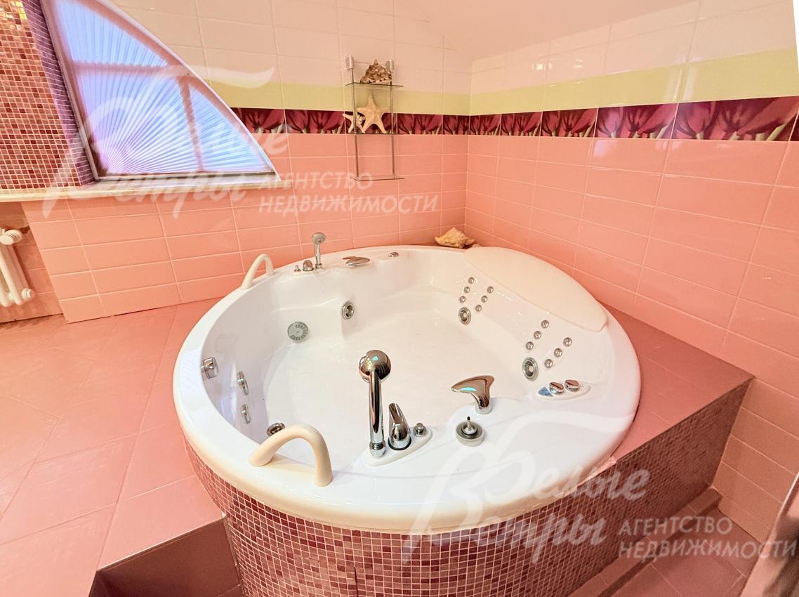 В санузле - круглая гидромассажная ванна (джакузи), облицованная мелкой мозаикой, и большое арочное окно