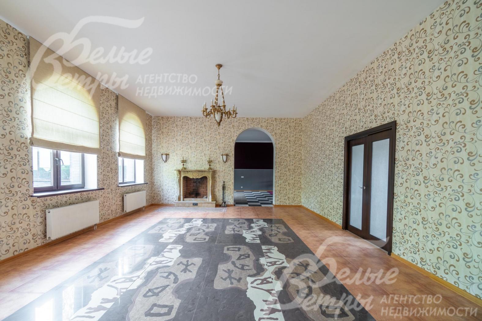 Гостиную украшают бронзовая люстра, камин, напольное панно из гранита 