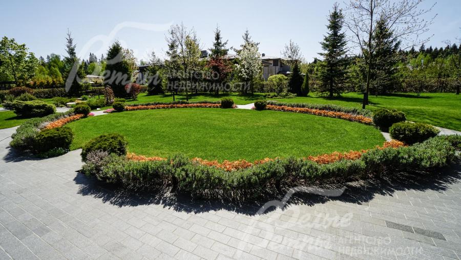 На участке выполнен профессиональный ландшафтный дизайн, в том числе высажен идеальный газон и множество цветников