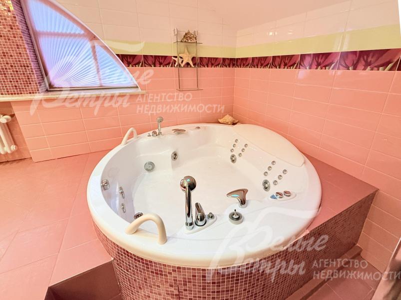 В санузле - круглая гидромассажная ванна (джакузи), облицованная мелкой мозаикой, и большое арочное окно