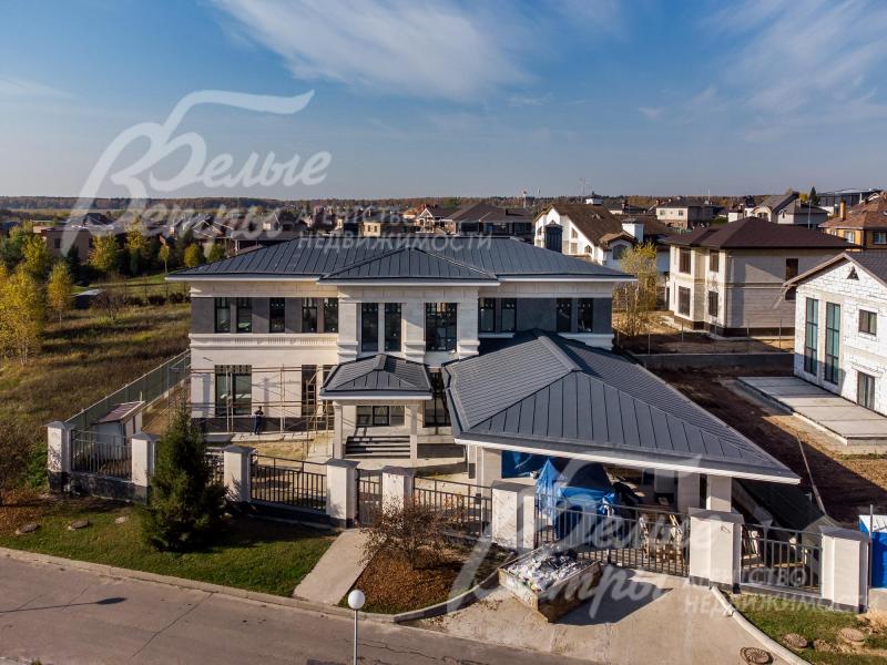 Выразительный натуральный камень и гранит на фасаде дома, стильные тёмно-серые витражи, гармонирующие с большими свесами крыши такого же цвета