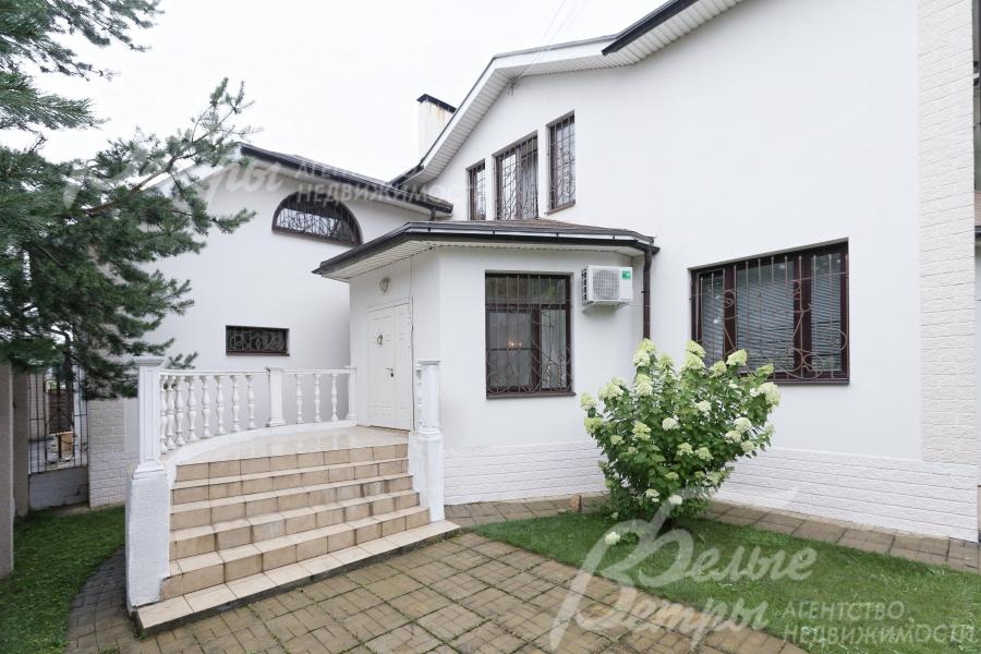 Главный вход в дом оформлен полукруглой лестницей, рядом - цветочная композиция