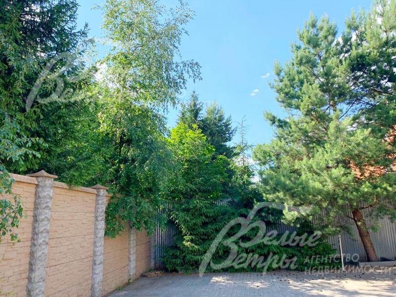 Участок огорожен высоким каменным забором, облицованным искусственным камнем в стиле дома