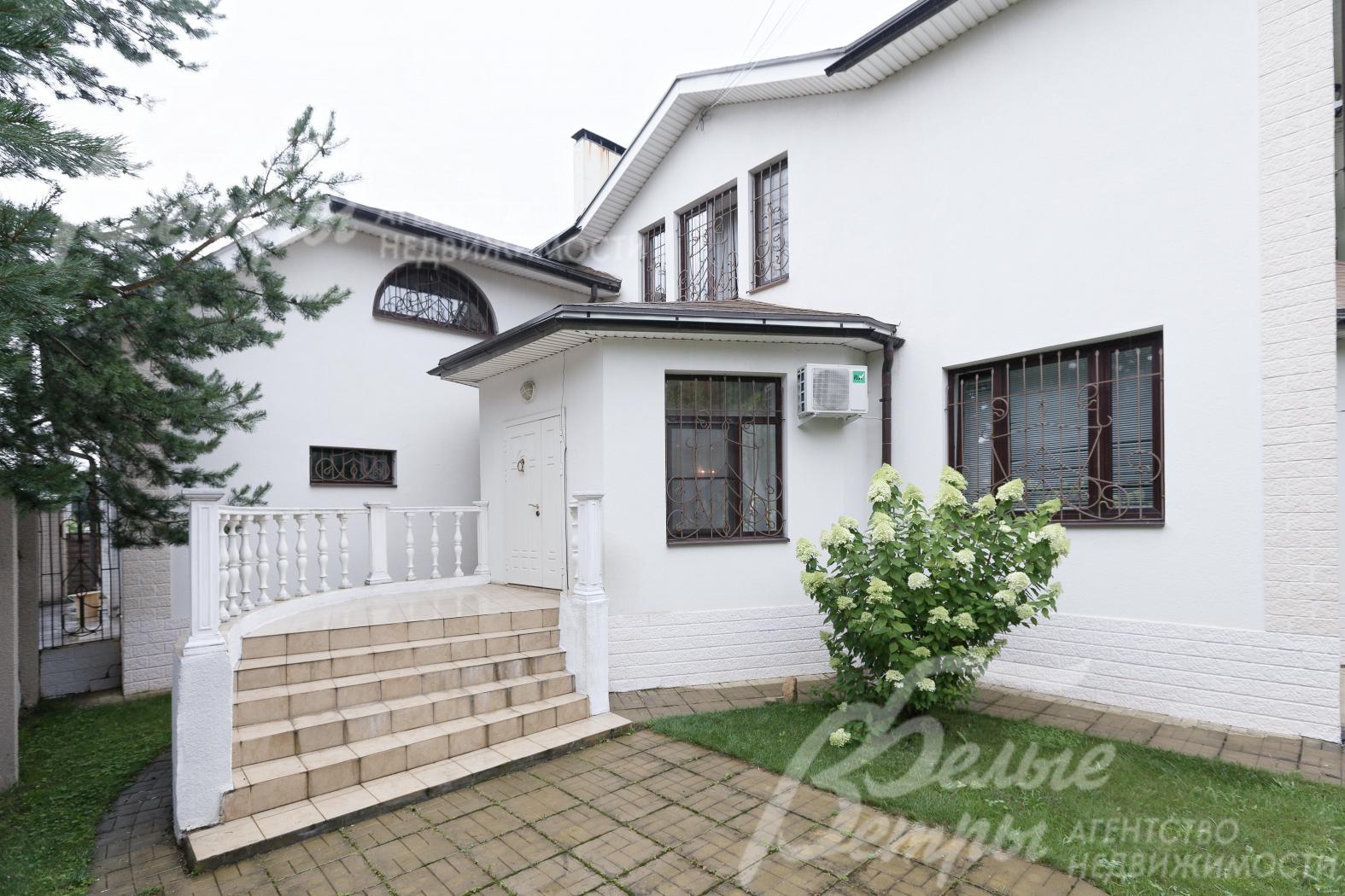 Главный вход в дом оформлен полукруглой лестницей, рядом - цветочная композиция