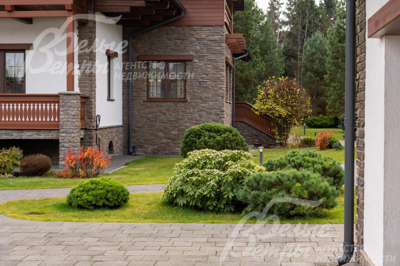 Часть фасада дома облицована искусственным камнем (справа - выход на участок из столовой)