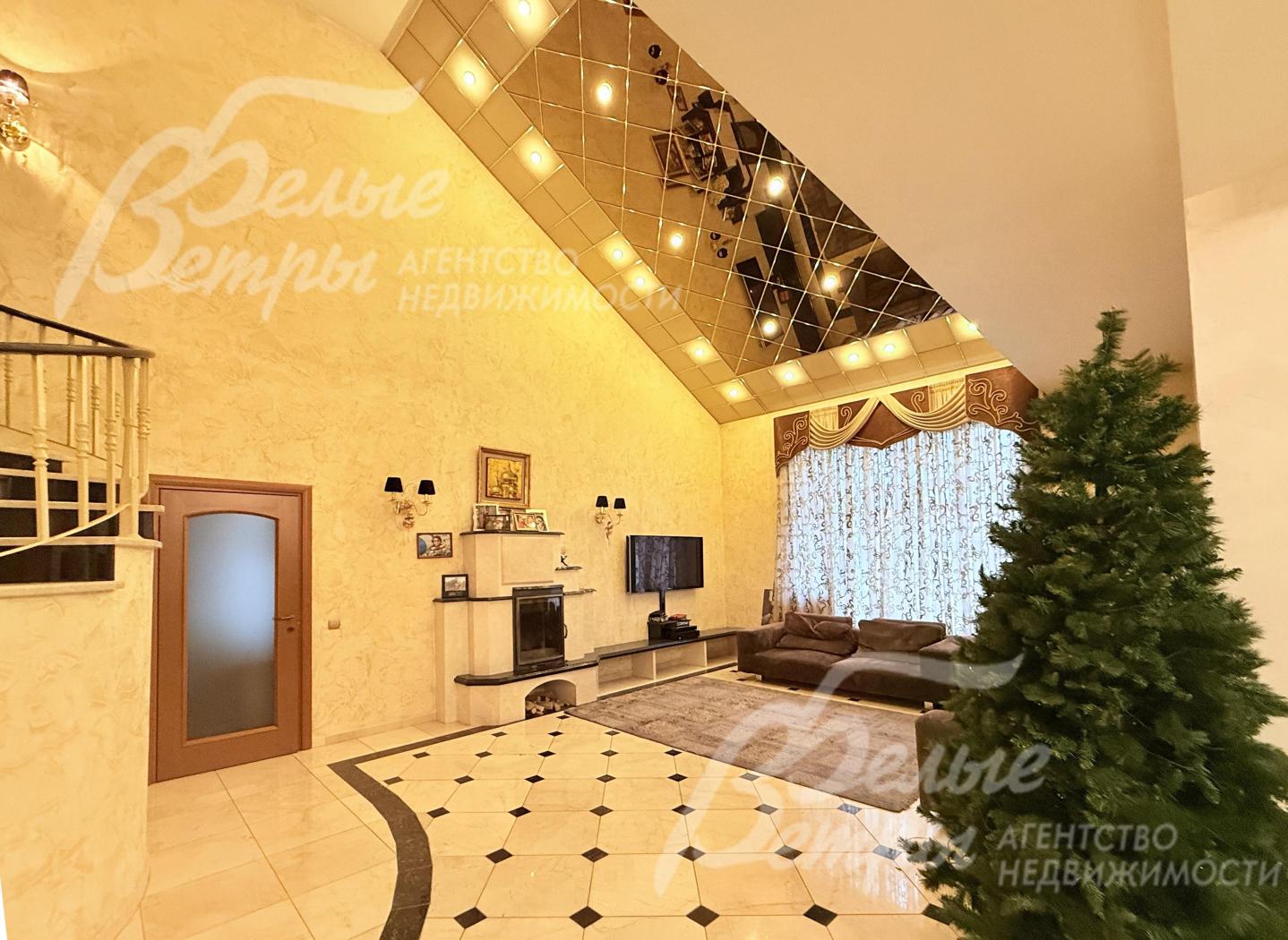 Интерьер каминного зала выполнен в элегантном стиле, включает диванную диванную группу с ковром, ТВ, зеркальный потолок второго света