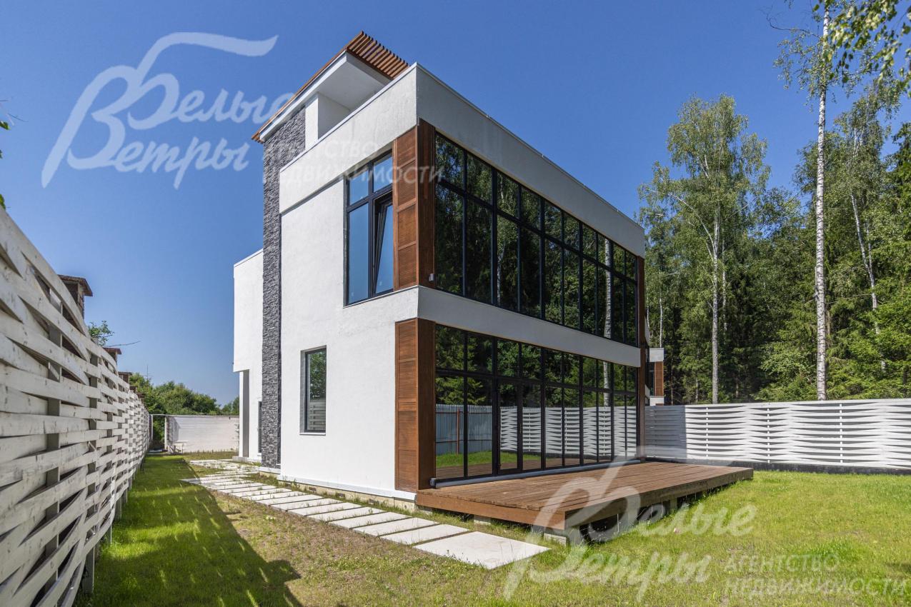 Тыльный фасад дома со стеклянной стеной и террасой