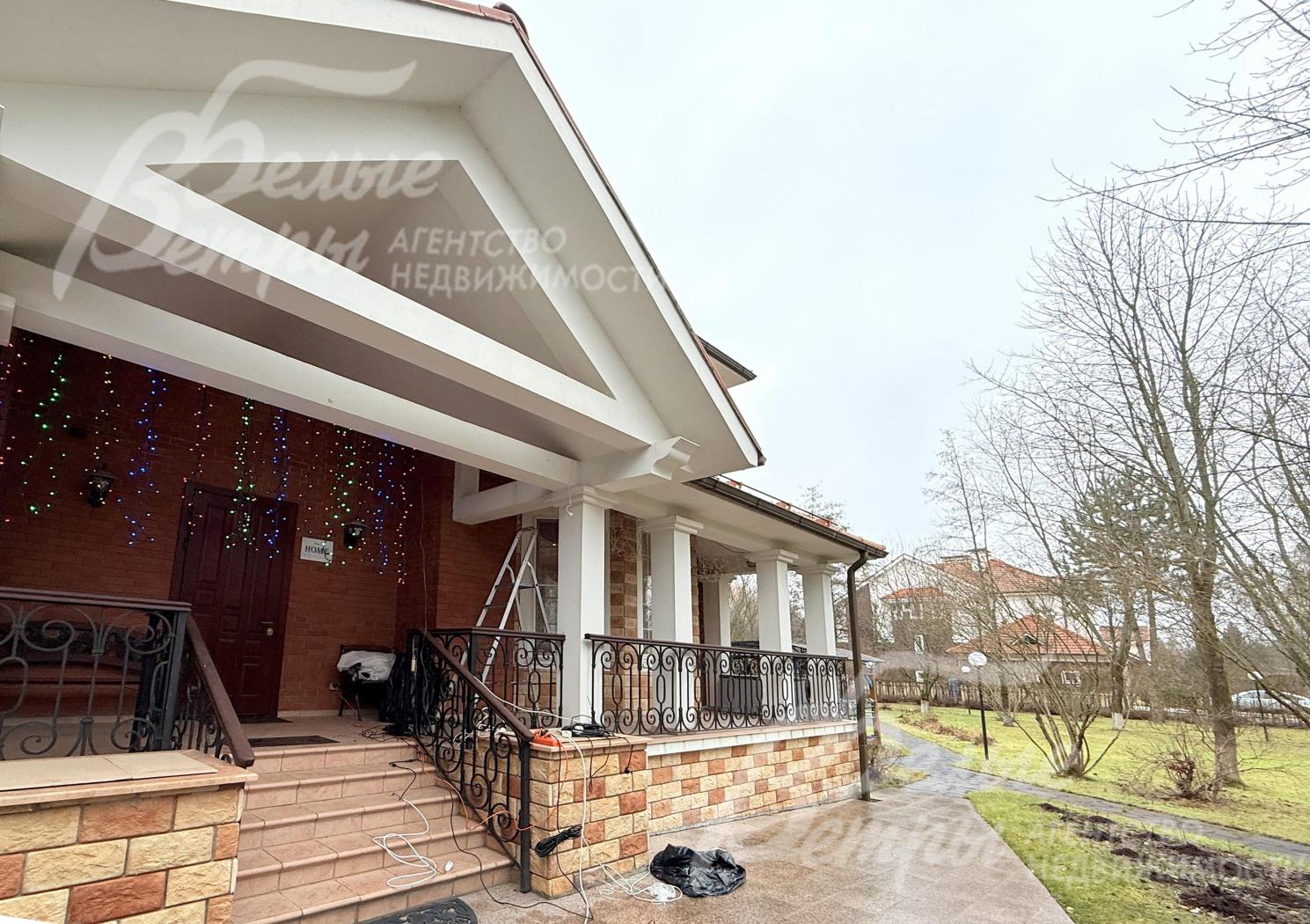 Архитектура террасы - с массивными белыми колоннами, крышей с широким свесом, перилами из кованого металла