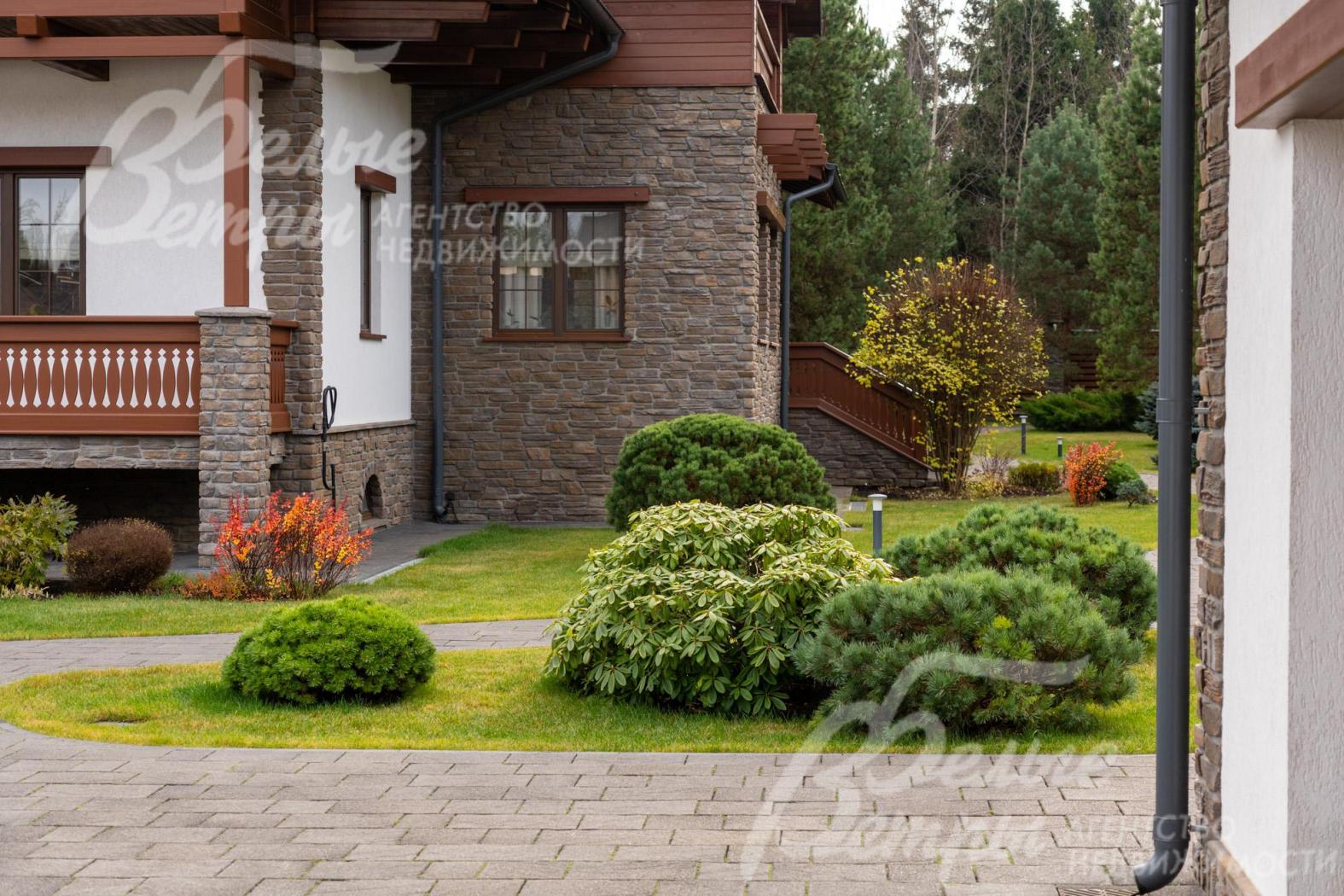 Часть фасада дома облицована искусственным камнем (справа - выход на участок из столовой)