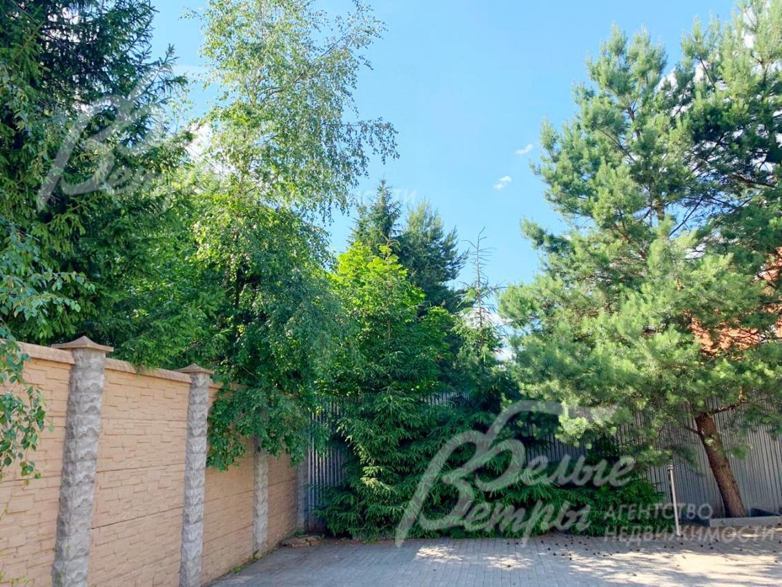 Участок огорожен высоким каменным забором, облицованным искусственным камнем в стиле дома