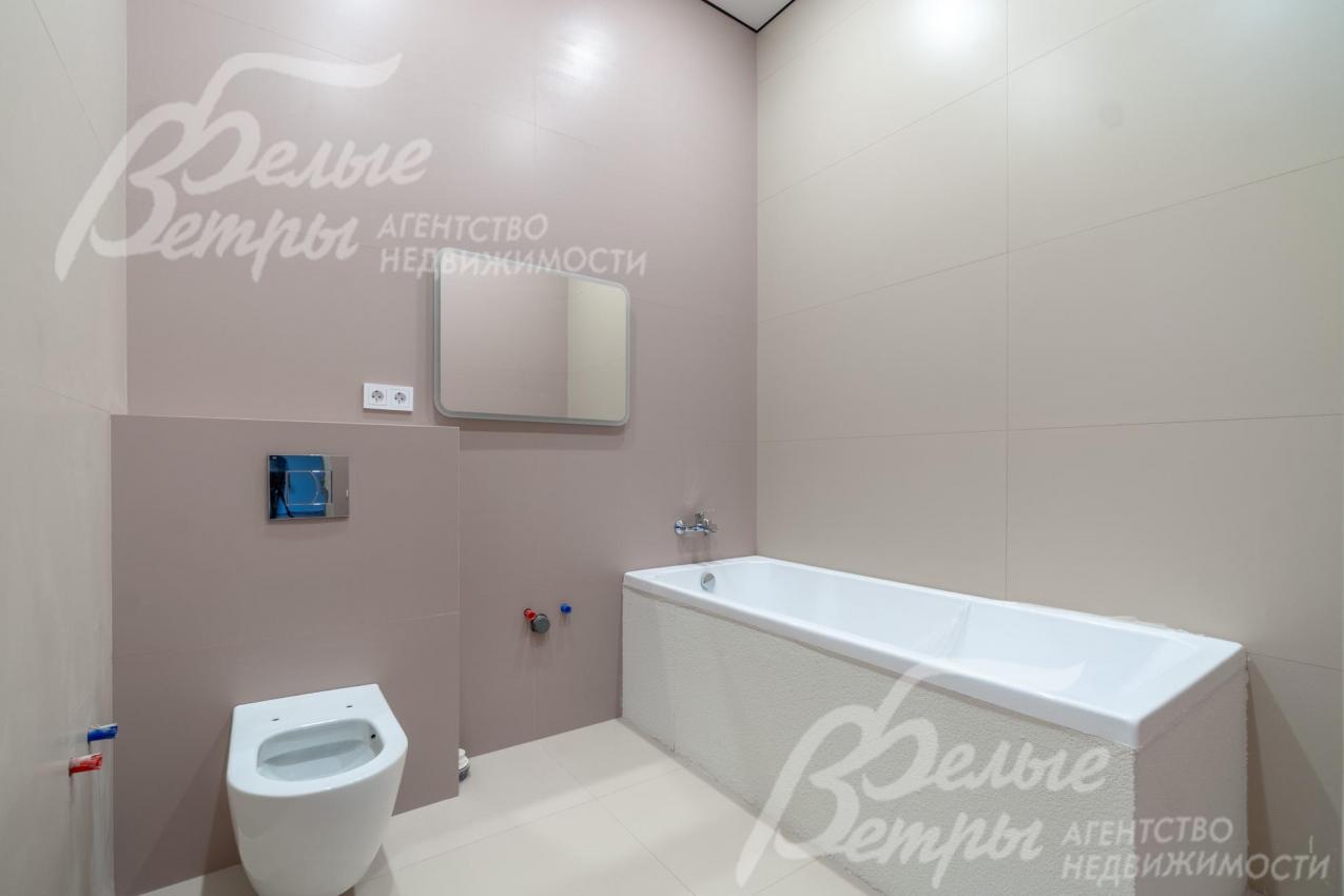 Один из санузлов на втором этаже с плиткой в светло-серых оттенках и с ванной