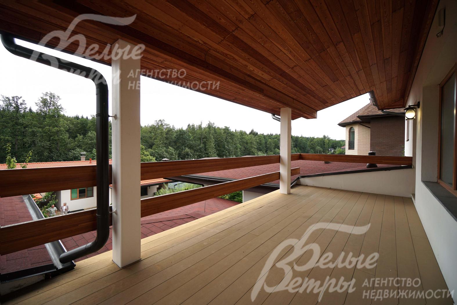 Крытая терраса на втором этаже с видом на участок и лес