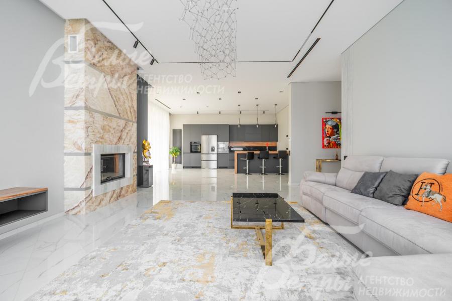 Просторная гостиная в светло-серых тонах с большим диваном и дровяным камином