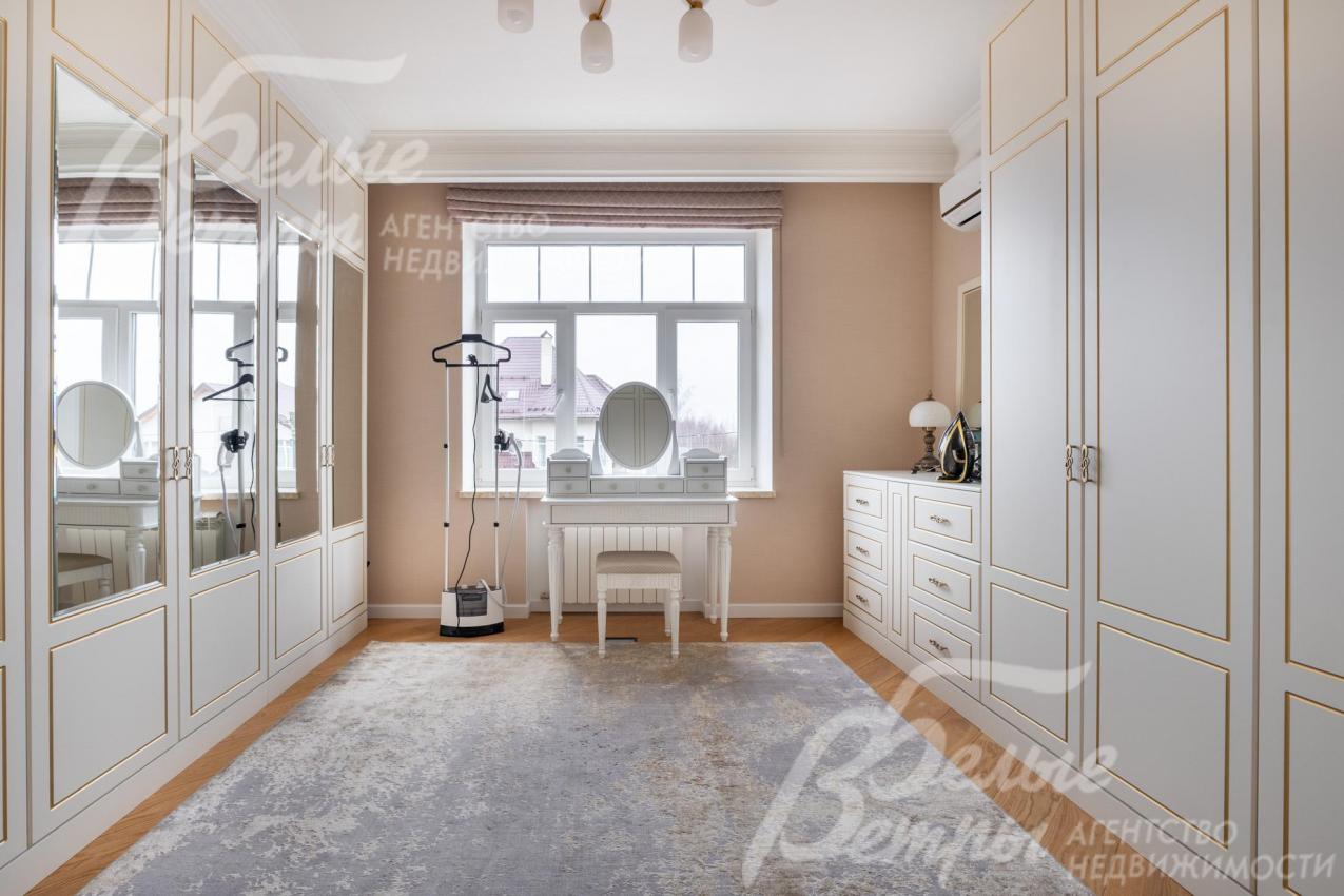 В доме на 2-м этаже - просторная гардеробная с элегантными шкафами и туалетным столиком у окна
